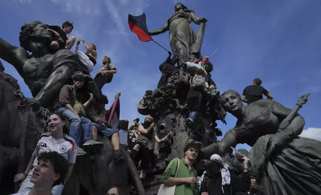 Protesters stand on a statue during the May Day demonstration, Thursday, May 1, 2025 in Paris. (AP Photo/Thibault Camus)