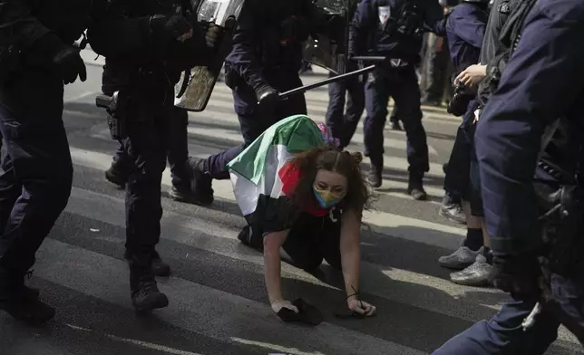 A protester is pushed down by police officers during incidents during the May Day demonstration, Thursday, May 1, 2025 in Paris. (AP Photo/Thibault Camus)