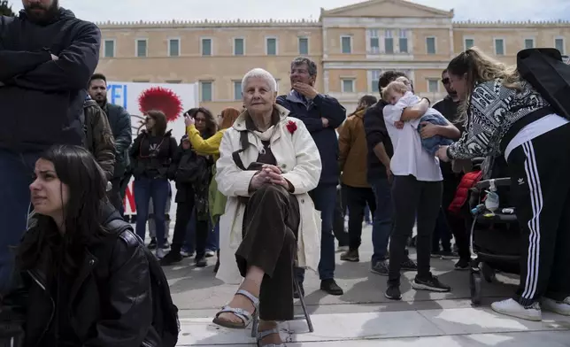 Olga sitting on a stool takes part in a rally organized by the communist party-affiliated PAME to mark May Day in Athens, Greece, Thursday, May 1, 2025. (AP Photo/Thanassis Stavrakis)