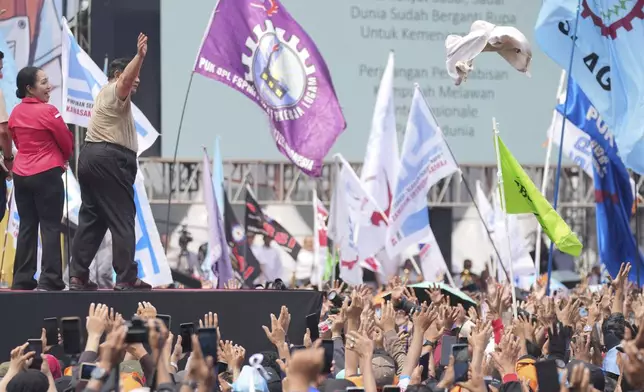 Indonesian President Prabowo Subianto, second left, throws his shirt to the crowd during a May Day rally at the National Monument in Jakarta, Indonesia, Thursday, May 1, 2025. (AP Photo/Tatan Syuflana)