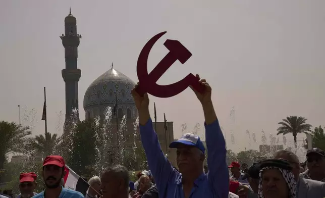 A supporter of the Iraqi Communist Party waves with a symbolic hammer and sickle and the communist flags as they take part in the May Day celebration in Baghdad, Iraq, Thursday, May 1, 2025. (AP Photo/Hadi Mizban)