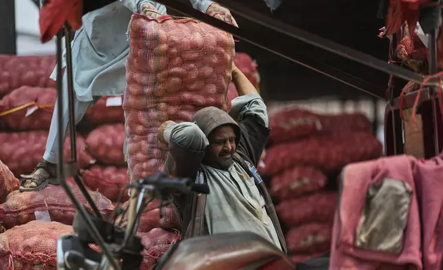 A laborer carries a sack of potatoes to load it into a mini truck at a wholesale vegetable market, during May Day in Islamabad, Pakistan, Thursday, May 1, 2025. (AP Photo/Anjum Naveed)