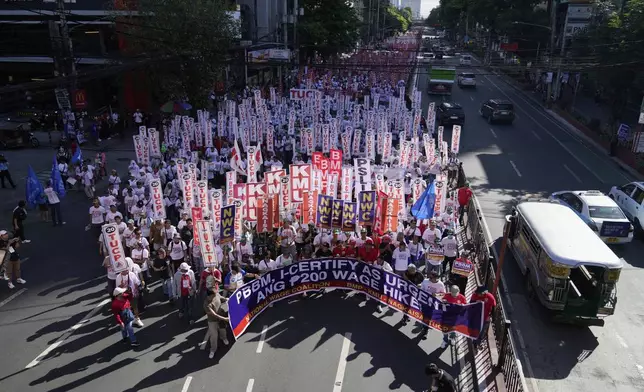 Activists and workers hold slogans during a May Day rally in Manila, Philippines, Thursday, May 1, 2025. (AP Photo/Aaron Favila)