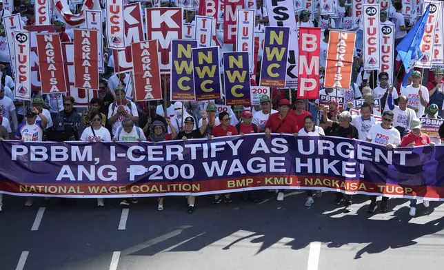 Activist and workers hold slogans during a May Day rally in Manila, Philippines, Thursday, May 1, 2025. (AP Photo/Aaron Favila)