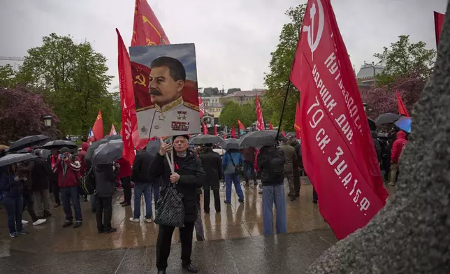 Russian Communist Party's supporters with a portrait of former Soviet leader Josef Stalin and red flags gather to mark Labor Day, also known as May Day, at the monument to 19th century German philosopher Karl Marx, near Red Square in Moscow, Russia, Thursday, May 1, 2025. (AP Photo/Alexander Zemlianichenko)