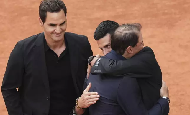 Rafa Nadal, second right, is hugged by Novak Djokovic as Roger Federer, left, look at them, during a farewell ceremony at center court Philippe-Chatrier, at the Roland-Garros stadium, in Paris, Sunday May 25, 2025. (AP Photo/Christophe Ena)