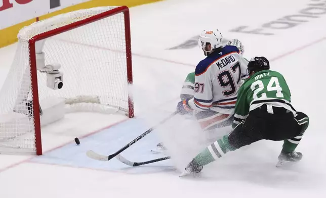 Edmonton Oilers center Connor McDavid (97) scores against Dallas Stars goaltender Casey DeSmith and center Roope Hintz (24) during the second period of Game 5 of the Western Conference finals in the NHL hockey Stanley Cup playoffs, Thursday, May 29, 2025, in Dallas. (AP Photo/Gareth Patterson)