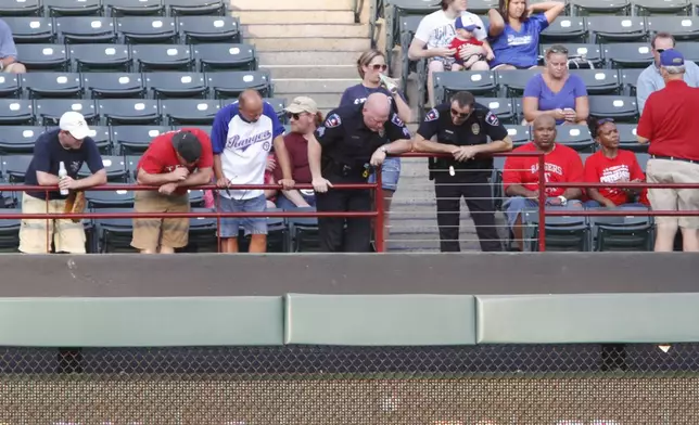 FILE - Police and fans look over the railing where a fan fell from the stands during the second inning of a baseball game between the Texas Rangers and the Oakland Athletics, Thursday, July 7, 2011, in Arlington, Texas. (AP Photo/Jeffery Washington, File)