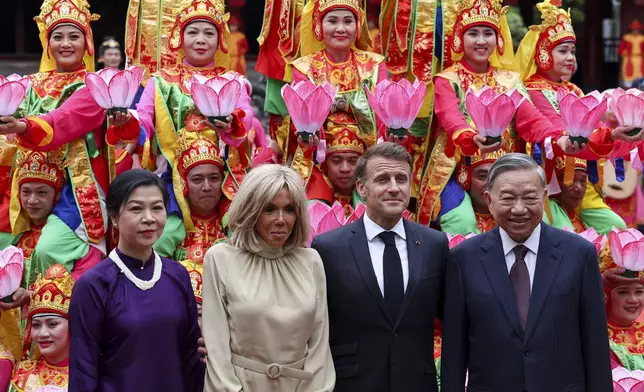 Vietnam's Communist Party General Secretary To Lam and his wife, Ngo Phong Ly, with French President Emmanuel Macron, center right, and his wife Brigitte Macron, center left, pose for a photo with traditional dance performers during a luncheon at Van Mieu, in Hanoi, Vietnam, Monday May 26, 2025. (Chalinee Thirasupa/Pool via AP)