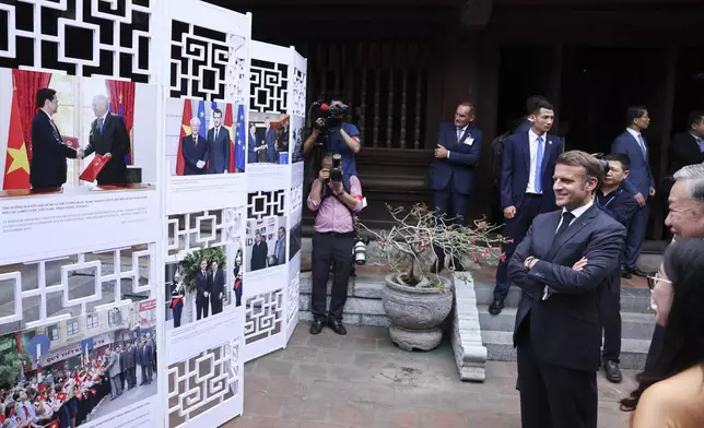 French President Emmanuel Macron looks at a display of photographs at a luncheon with Vietnam's Communist Party General Secretary To Lam at Van Mieu, in Hanoi, Vietnam, Monday May 26, 2025. (Chalinee Thirasupa/Pool via AP)