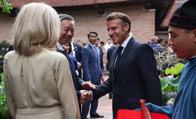 Vietnam's Communist Party General Secretary To Lam shakes hands with French President Emmanuel Macron, as his wife, Brigitte Macron, looks on, ahead of a luncheon at Van Mieu, in Hanoi, Vietnam, Monday May 26, 2025. (Chalinee Thirasupa/Pool via AP)