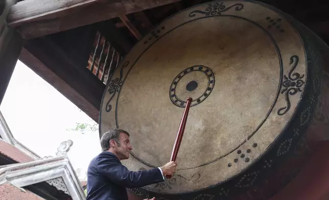 French President Emmanuel Macron beats a drum at Van Mieu temple during a luncheon with Vietnam's Communist Party General Secretary To Lam during Macron's first official trip to the country, in Hanoi, Vietnam, Monday, May 26, 2025. (Chalinee Thirasupa/Pool Photo via AP)
