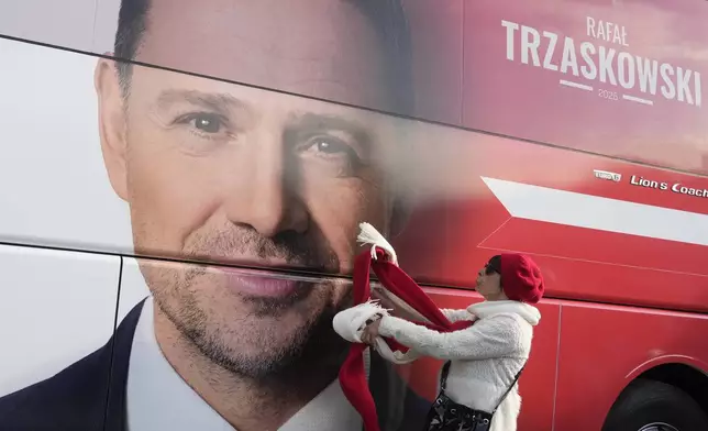 A woman stands next to a campaign poster of Warsaw Mayor Rafał Trzaskowski, a liberal candidate in Poland's presidential election, in Lodz, Poland, Friday, May 9, 2025. (AP Photo/Czarek Sokolowski)