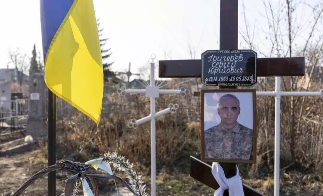 A portrait of Serhii Hryhoriev, a Ukrainian prisoner of war who died in Russia, is seen next to his grave in Pyriatyn, Ukraine, March 9, 2025. (AP Photo/Alex Babenko)