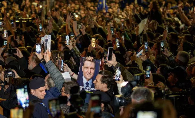 Supporters of presidential candidate Nicusor Dan cheer holding an electoral poster after he won the second round of the country's presidential election redo in Bucharest, Romania, early Monday, May 19, 2025. (AP Photo/Andreea Alexandru)