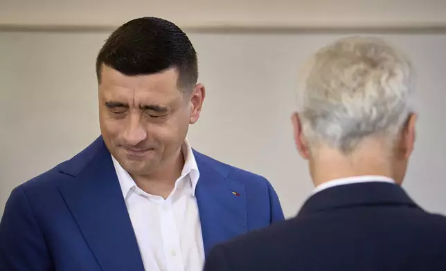 Presidential candidate George Simion grimaces next to Calin Georgescu, winner of the first round of last year's annulled election, before casting his vote in the second round of the country's presidential election redo in Mogosoaia, Romania, Sunday, May 18, 2025. (AP Photo/Vadim Ghirda)