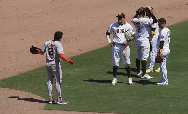 San Francisco Giants shortstop Willy Adames, left, jokes with San Diego Padres third baseman Manny Machado, center, and members of the Padres infield as they wait for a play under review during the sixth inning of a baseball game Wednesday, April 30, 2025, in San Diego. (AP Photo/Gregory Bull)