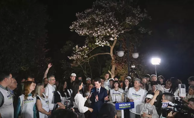 Presidential candidate Nicusor Dan speaks to media, surrounded by supporters, after polls closed in the first round of the country's presidential election redo in Bucharest, Romania, Sunday, May 4, 2025. (AP Photo/Eduard Vinatoru)