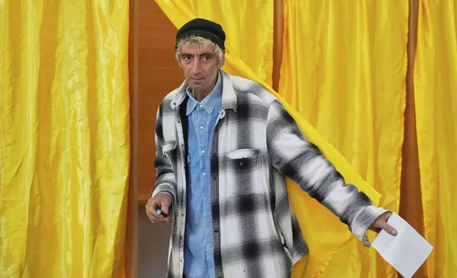 A man exits a voting cabin before casting his vote in the first round of the presidential election redo in Mogosoaia, Romania, Sunday, May 4, 2025. (AP Photo/Vadim Ghirda)