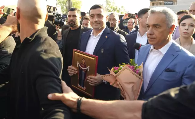 Presidential candidate George Simion, left, holds a religious icon as he walks with Calin Georgescu, winner of the first round of last year's annulled election, after casting his vote in the first round of the presidential election redo in Mogosoaia, Romania, Sunday, May 4, 2025. (AP Photo/Vadim Ghirda)