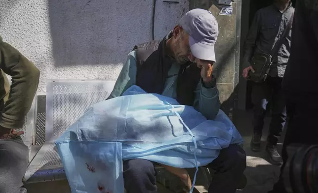 A man mourns over the body of a victim of an Israeli army strike on a restaurant, which killed at least 29 people, at the Shifa hospital in Gaza City, Wednesday, May 7, 2025.(AP Photo/Jehad Alshrafi)