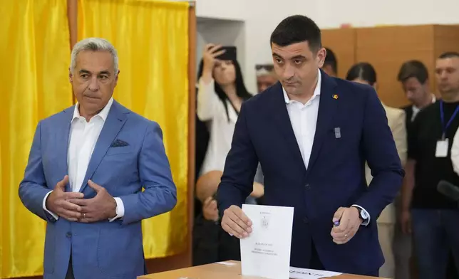 Presidential candidate George Simion, right, casts his vote next to Calin Georgescu, winner of the first round of last year's annulled election, during the first round of the presidential election redo in Bucharest, Romania, Sunday, May 4, 2025. (AP Photo/Vadim Ghirda)