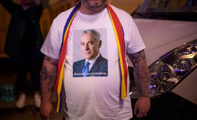 A man wears a t-shirt showing Calin Georgescu, winner of the first round of last year's voided election outside the headquarters of presidential candidate George Simion, after polls closed during the first round of the country's presidential election redo in Bucharest, Romania, Sunday, May 4, 2025. (AP Photo/Andreea Alexandru)
