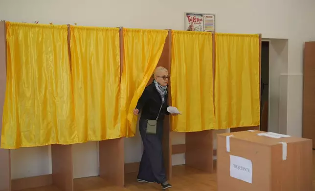 A woman exits a voting booth before casting her vote in the first round of the presidential election redo in Bucharest, Romania, Sunday, May 4, 2025. (AP Photo/Vadim Ghirda)