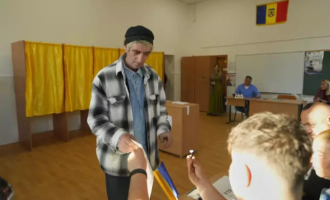 A man receives a voting stamp before casting his vote in the first round of the presidential election redo in Bucharest, Romania, Sunday, May 4, 2025. (AP Photo/Vadim Ghirda)