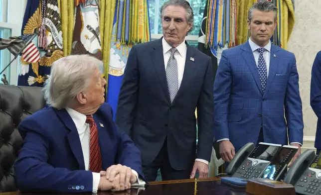 President Donald Trump and Defense Secretary Pete Hegseth listen as Interior Secretary Doug Burgum speaks in the Oval Office of the White House, Friday, May 23, 2025, in Washington. (AP Photo/Evan Vucci)