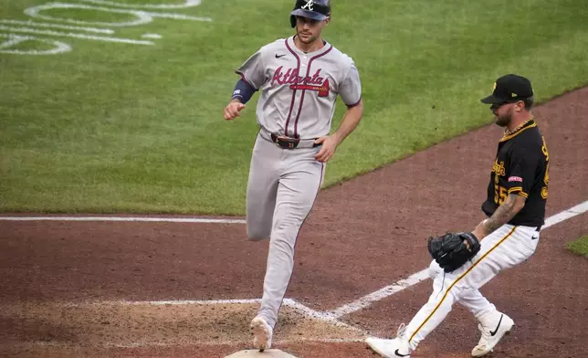 Atlanta Braves' Matt Olson, left, scores from third base on a wild pitch by Pittsburgh Pirates pitcher Chase Shugart, right, during the 11th inning of a baseball game in Pittsburgh, Saturday, May 10, 2025. (AP Photo/Gene J. Puskar)