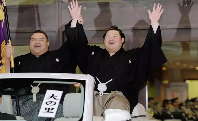 Onosato, right, raises hands for his victory of a sumo wrestling tournament during a celebratory parade at Ryogoku Kokugikan arena in Tokyo, Sunday, May 25, 2025. (Daiki Katagiri/Kyodo News via AP)