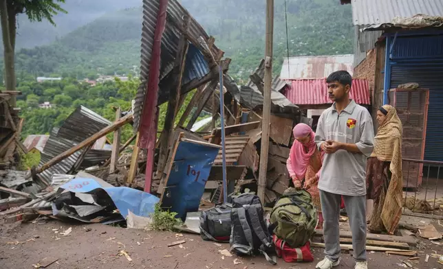 A family waits for transportation as they leave following overnight shelling from Pakistan at Gingal village in Uri district, Indian controlled Kashmir, Friday, May 9, 2025. (AP Photo/Dar Yasin)