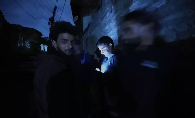 Kashmiri boys watch online news on their cell phone during a blackout after residents reported hearing explosions and sirens in Srinagar, Indian controlled Kashmir, Friday, May 9, 2025. (AP Photo/Mukhtar Khan)