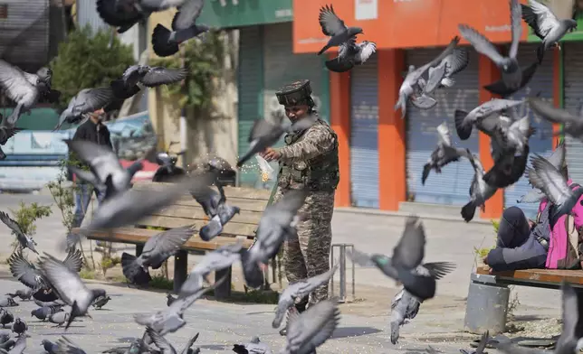 An Indian soldier feeds pigeons at a market, day after India and Pakistan agreed to a ceasefire Saturday following U.S.-led talks to end the most serious military confrontation between the nuclear-armed rivals in decades, in Srinagar, in Indian controlled Kashmir, Sunday, May 11, 2025.(AP Photo/Mukhtar Khan)