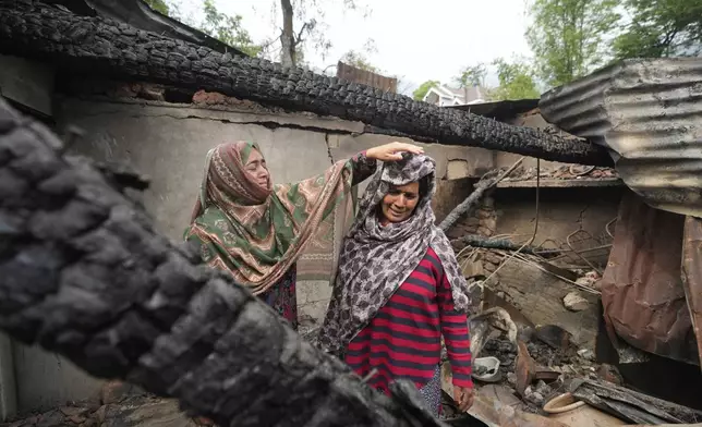 A relative comforts Rubina Begum as she wails inside her house damaged by Pakistani artillery shelling, at Salamabad village in Uri, north of Srinagar, Indian controlled Kashmir, Thursday, May 8, 2025. (AP Photo/Mukhtar Khan)