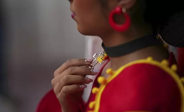 A woman in traditional Spanish garb touches her cross necklace before a bullfight in Aguascalientes, Mexico, Sunday, April 27, 2025. (AP Photo/Eduardo Verdugo)