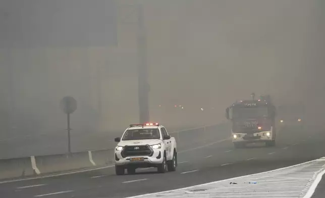 Israeli fire department crews drives through smoke from a burning fire on the freeway near Jerusalem, Wednesday, April 30, 2025. (AP Photo/Mahmoud Illean)