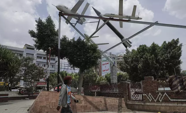 A Yemeni man walks past a monument featuring mock rockets in Sanaa, Yemen, Monday, May 5, 2025. (AP Photo/Osamah Abdulrahman)