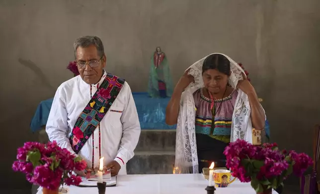 FILE - Deacon Juan Pérez Gómez, accompanied by his wife Crecencia López, stands at the altar during a Mass honoring the late Pope Francis, in Simojovel, Mexico, April 27, 2025. (AP Photo/Isabel Mateos, File)