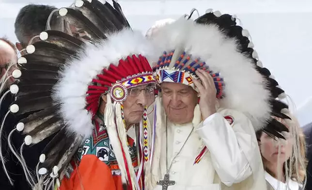 FILE - Pope Francis dons a headdress during a meeting with Indigenous communities, including First Nations, Metis and Inuit, at Our Lady of Seven Sorrows Catholic Church in Maskwacis, near Edmonton, Canada, July 25, 2022. (AP Photo/Gregorio Borgia, File)