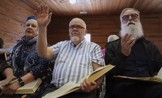 From left, Lisa Bennett, Wade Kotter, and David Stead, Bennett's husband, sing in the alto section during a Sacred Harp singing event at Holly Springs Primitive Baptist Church in Bremen, Ga., on Saturday, March 22, 2025. (AP Photo/Jessie Wardarski)