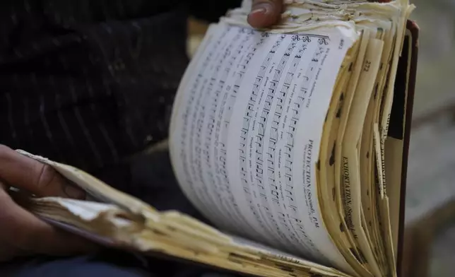 Isaac Green, 34, flips through his personal copy of "The Sacred Harp," a shape-note hymnal linked to a more than 180-year-old American folk singing tradition, at Holly Springs Primitive Baptist Church in Bremen, Ga., on Sunday, March 23, 2025. The 1991 edition has undergone a multi-year revision process conducted by a nine-member committee and will be released by the Sacred Harp Publishing Company in September. (AP Photo/Jessie Wardarski)