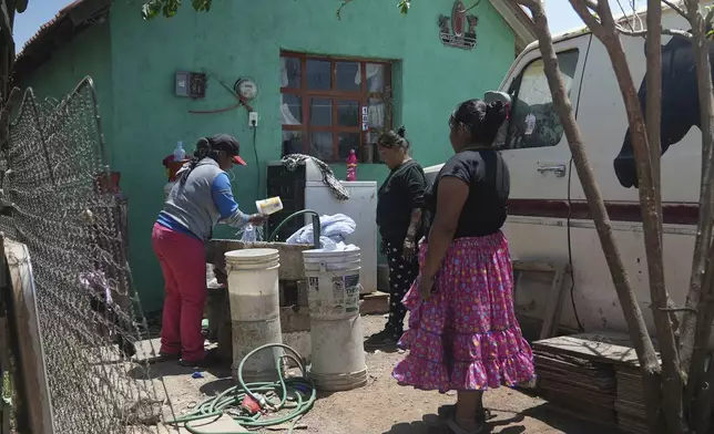 Tarahumara Indigenous woman Gloria Vega, right, watches a neighbor wash clothes outside her home in Cuauhtemoc, Mexico, Thursday, May 1, 2025. (AP Photo/Martin Silva Rey)