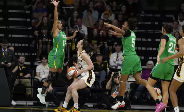 Indiana Fever guard Caitlin Clark, second from left, drives to the basket between Brazil guard Carina Martins, left, and forward Ayla McDowell (5) during the first half of an exhibition women's basketball game, Sunday, May 4, 2025, in Iowa City, Iowa. (AP Photo/Charlie Neibergall)
