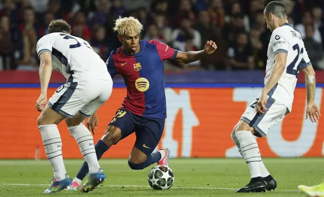 Barcelona's Lamine Yamal, center, is challenged by Inter Milan's Carlos Augusto, left, and Inter Milan's Henrikh Mkhitaryan during the Champions League semifinal first leg soccer match between Barcelona and Inter Milan at the Lluis Companys Olympic Stadium in Barcelona, Spain, Wednesday, April 30, 2025. (AP Photo/Joan Monfort)