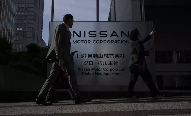 Visitors walk past Nissan signage at Nissan headquarters in Yokohama, Tuesday, May 13, 2025. (AP Photo/Louise Delmotte)