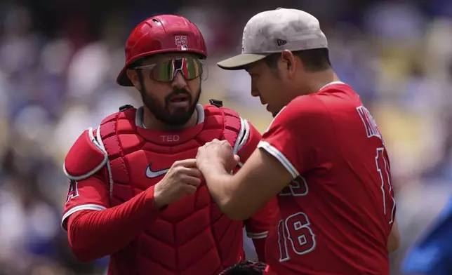 Los Angeles Angels catcher Travis d'Arnaud, left, and starting pitcher Yusei Kikuchi congratulate each other after the second inning of a baseball game against the Los Angeles Dodgers, Sunday, May 18, 2025, in Los Angeles. (AP Photo/Mark J. Terrill)