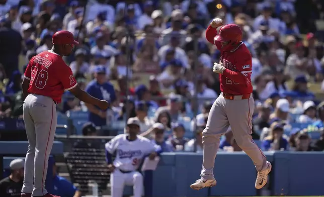 Los Angeles Angels' Travis d'Arnaud, right, is congratulated by third base coach Bo Porter after hitting a solo home run during the eighth inning of a baseball game against the Los Angeles Dodgers, Sunday, May 18, 2025, in Los Angeles. (AP Photo/Mark J. Terrill)