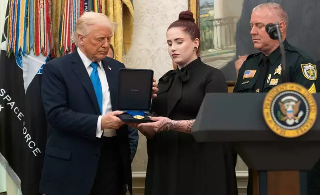 President Donald Trump presents a Medal of Sacrifice to Alexandria Diaz, center, honoring her late father Deputy Sheriff Ignacio "Dan" Diaz, during a ceremony in the Oval Office at the White House, Monday, May 19, 2025, in Washington. (AP Photo/Manuel Balce Ceneta)